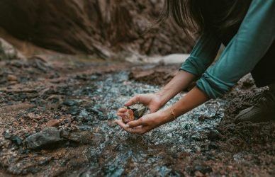 a person kneeling down and holding a rock in their hands